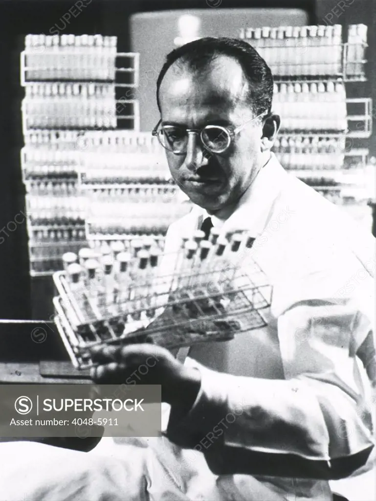 Jonas E. Salk (1914-1995), American medical researcher who developed the first Polio vaccine, holding tray of test tubes. Ca. 1955.