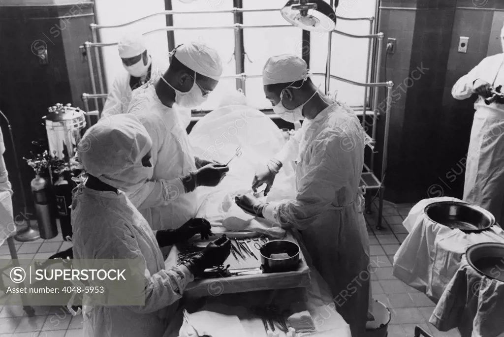 Operation at Provident Hospital, Chicago, Illinois in 1941. showing increased use of antiseptic procedures. The operating theater has specialized lighting, doctors are using gloves, full masks and head covers. Photo by Russell Lee.