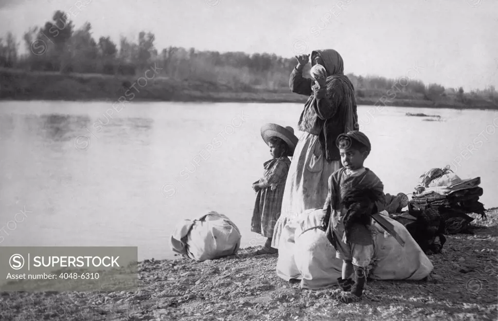 Mexican women with her children and bundles on the edge of the Rio Grande River. Ca. 1910.