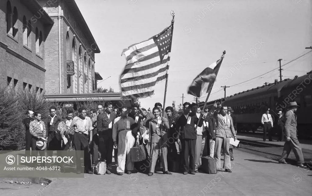 Mexican agricultural laborers arriving in Stockton, California, displaying flags of the United States and Mexico.  The were admitted under the government sponsored Bracero program which  regulated temporary laborers from Mexico to ease wartime labor shortages. May 1943.