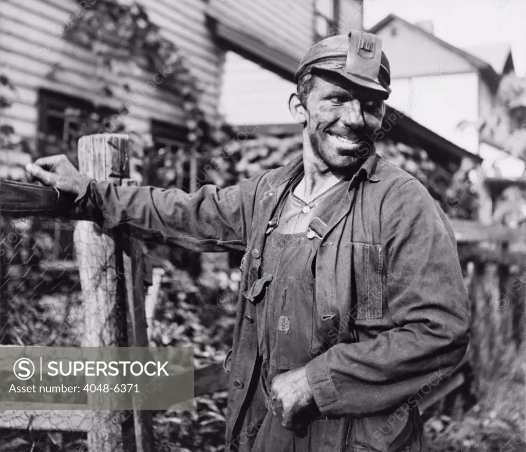 Smiling Polish-American miner, in work clothes and covered with coal dust, arriving home from work in Capels, West Virginia. 1938 photo by Marion Post Wolcott.