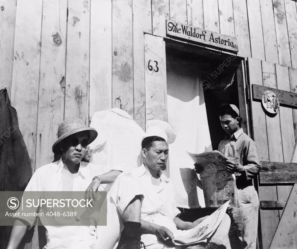 Japanese American men from Seattle, Washington sit outside a barracks during their four month stay at Puyallup Assembly Center in 1942. The Relocation Authority named the temporary internment facility, 'Camp Harmony.' The internees in turn named their barracks the 'The Waldorf Astoria.'