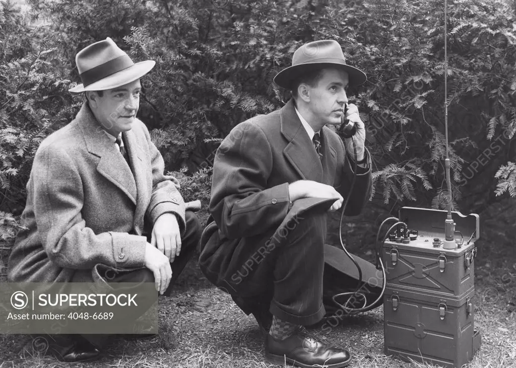 FBI agent with an huge portable phone during a kidnapping stakeout. Ca. 1940s.