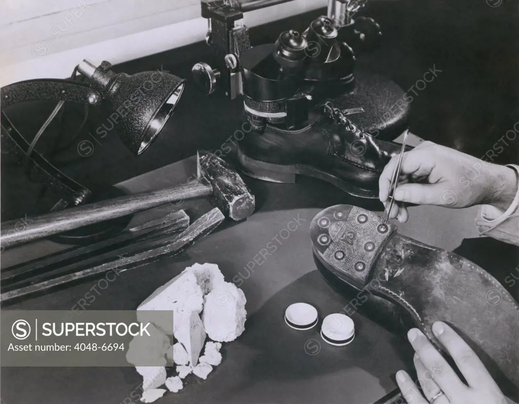 FBI forensic science. A technician removing safe insulation from the shoes of a burglary suspect at the FBI lab in 1954.