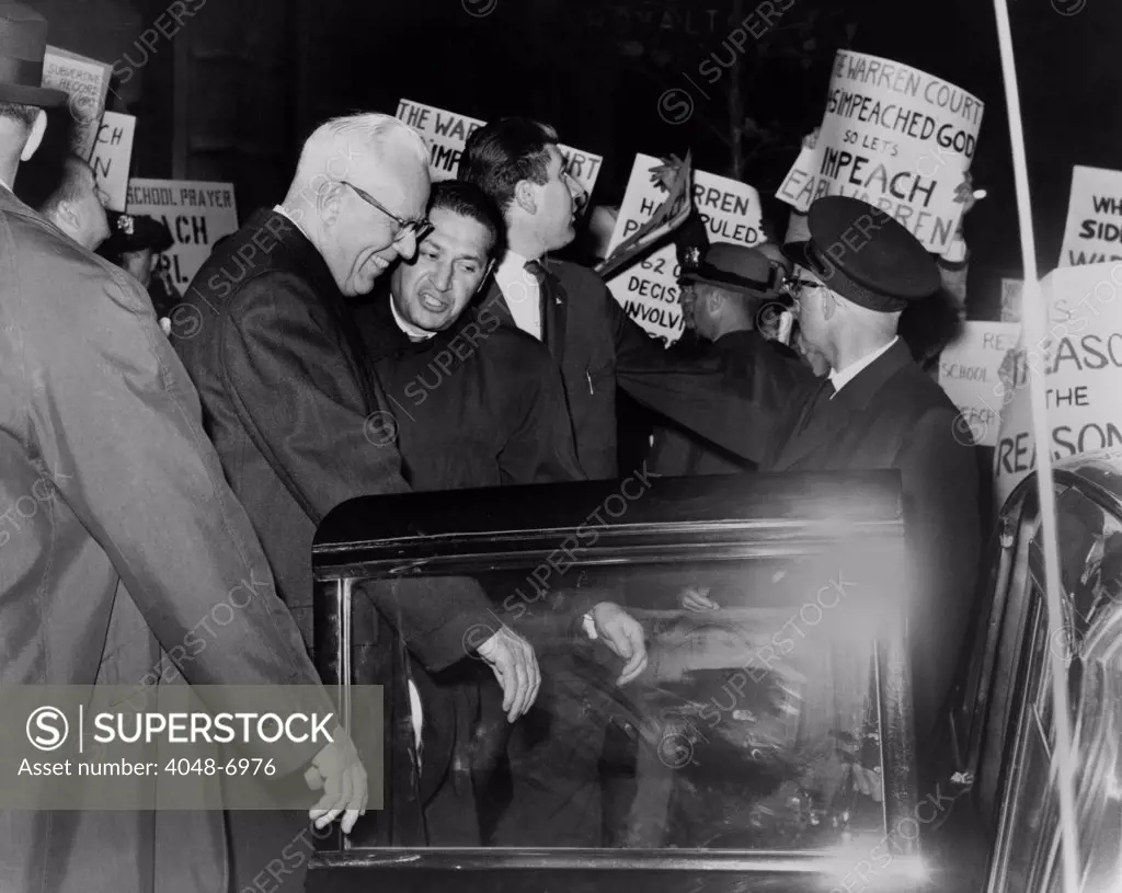 Chief Justice Earl Warren is escorted through crowd of protestors carrying placards attacking the Supreme Court's 1963 ruling (Abington School District v. Schempp) to prohibit prayer in U.S. public schools.