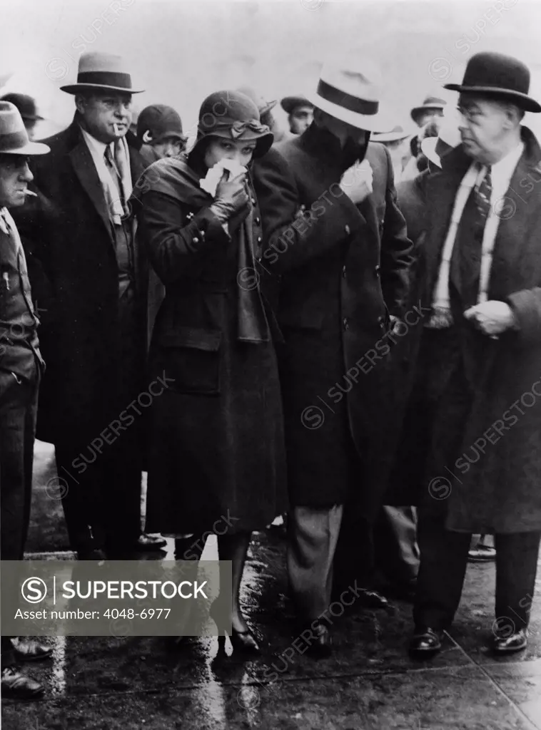Mr. and Mrs. Vincent Coll, hiding their faces from photographers as they leave court after Coll was acquitted of the murder of five year old, Michael Vengalli. December 1931.