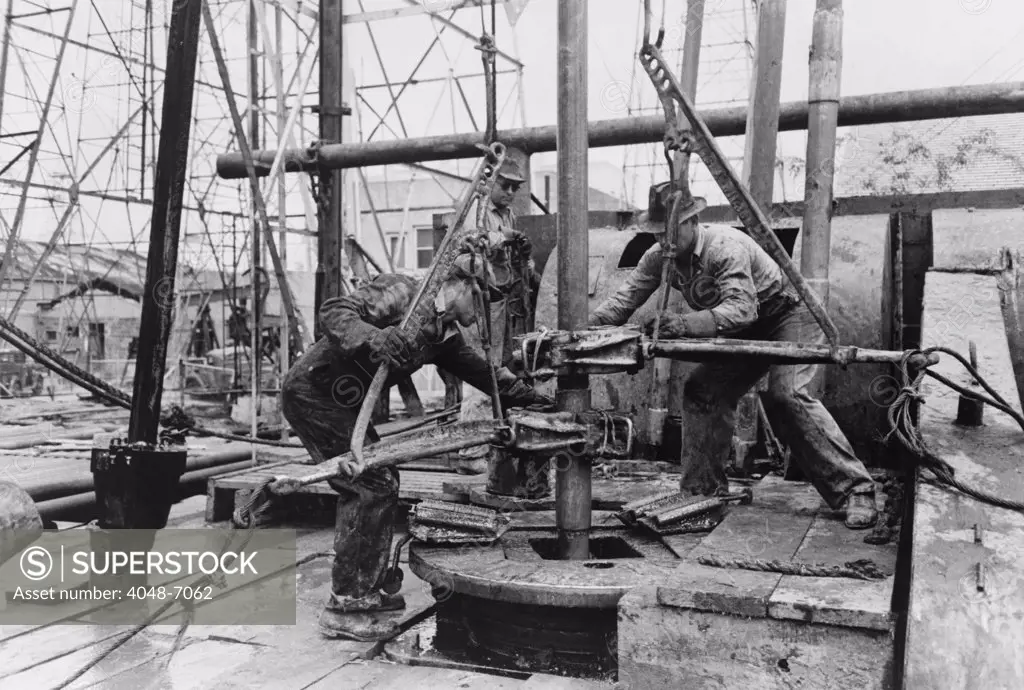 Oil rig workers, called roughnecks, at work, loosening sections of pipe on an drilling platform, Kilgore, Texas. 1939 Photo by Russell Lee.