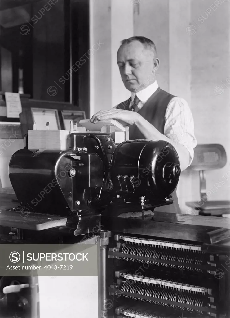 Man loading punch cards into a tabulating machine used in the 1920 United States census. It was a predecessor of electronic computers, and worked by mechanically reading punch cards with coded information.