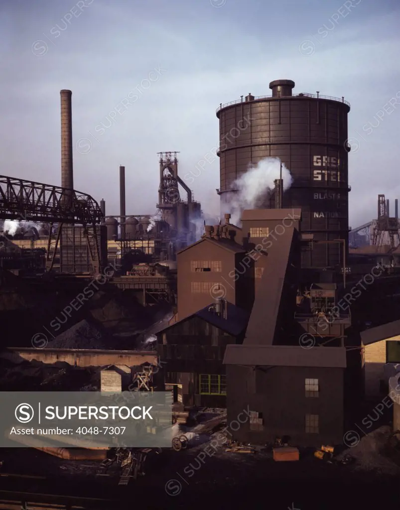 Hanna furnaces of the Great Lakes Steel Corporation, Detroit, Michigan. The tank stores gas from the coke oven. Square building and extension in middle ground is where coal is fed to the coke oven.
