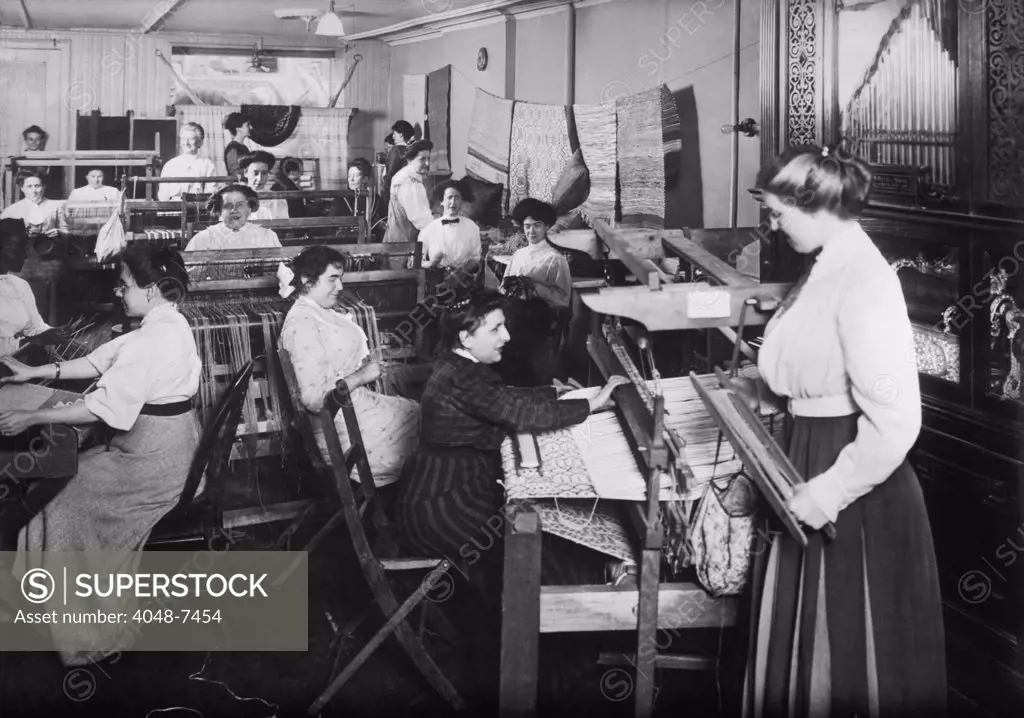 Blind women weaving at looms accompanied by an orchestrion, a self playing musical instrument, at right. Photo taken by Byron Company for the New York Association for the Blind.