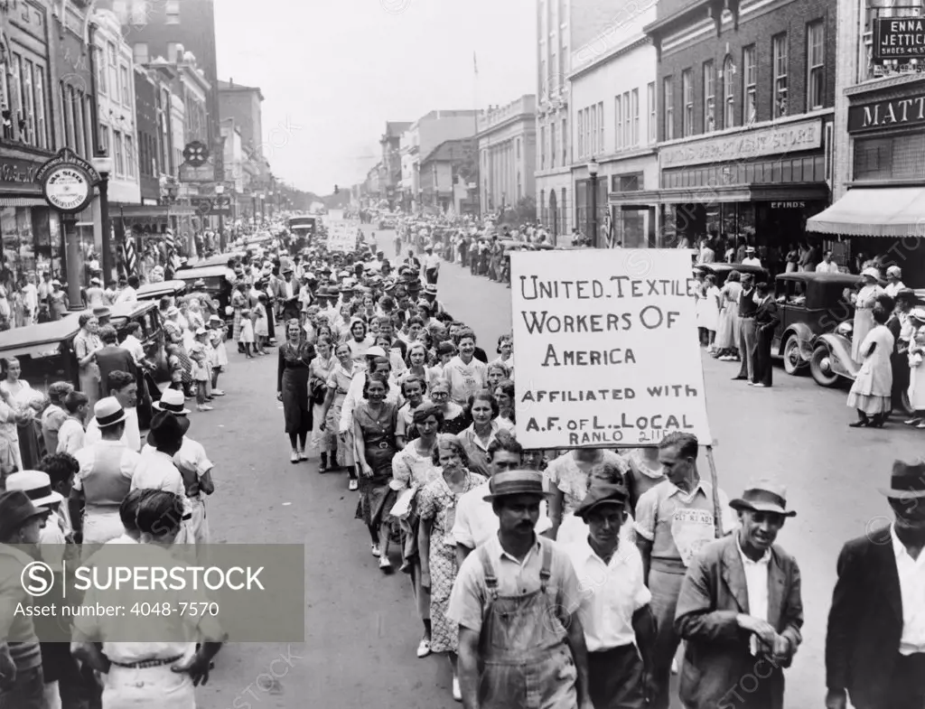 Striking Southern textile workers celebrate Labor Day with a parade and sign announcing their affiliation with the American Federation of Labor in 1934. Gastonia, North Carolina.