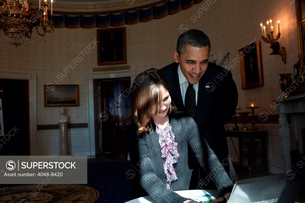 President Barack Obama looks over the shoulder of Hannah Wyman, 11, as she demonstrates her grand prize-winning project in the Blue Room, Feb. 7, 2012, during the second annual White House Science Fair.