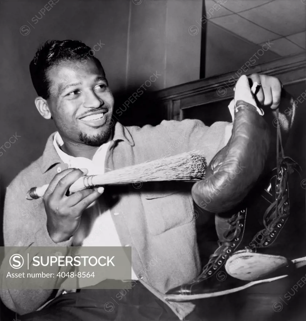 Sugar Ray Robinson dusting off his boxing gloves and shoes in a publicity photo for his 1954 comeback to professional boxing. He returned to boxing after a two year attempt to break into show business as a singer-tap dancer.