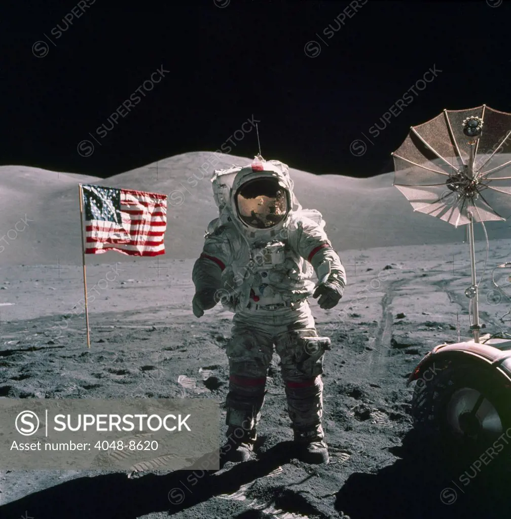 Apollo 17 Astronaut stands between a US flag and the Lunar Rover during the last US manned mission to the Moon. Dec. 12, 1971.