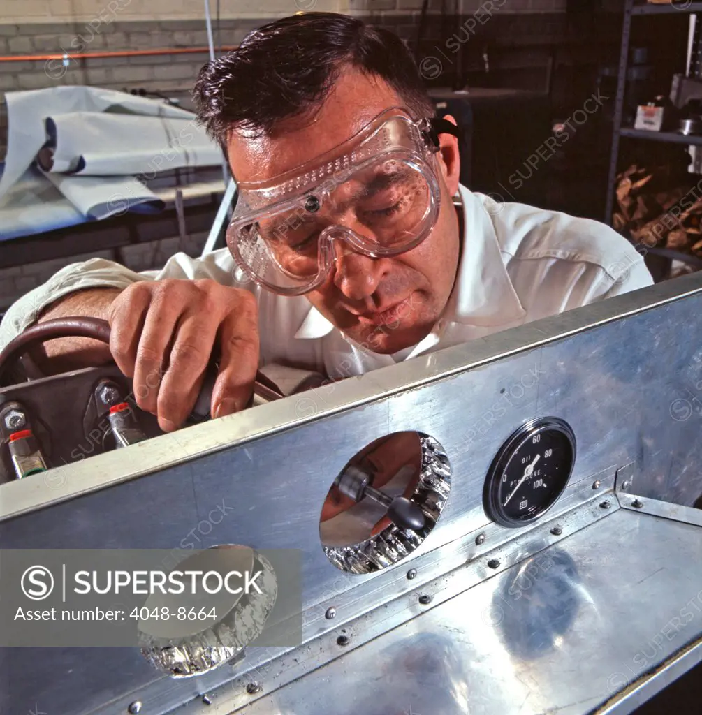 Ford engineer adjusts holes for dashboard instruments on a racing-car chassis made of honeycomb aluminum, a material full of air and resistant to metal fatique. Ford Motor Company, Dearborn Michigan, 1966. Photo: John G. Zimmerman Archive/Courtesy Everett Collection