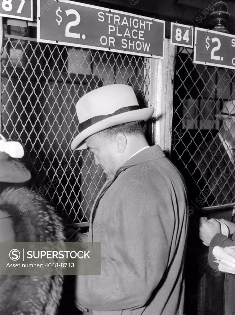 J. Edgar Hoover placing a bet at the two dollar window. It was opening day at Bowie race track, Maryland, April 1, 1938.