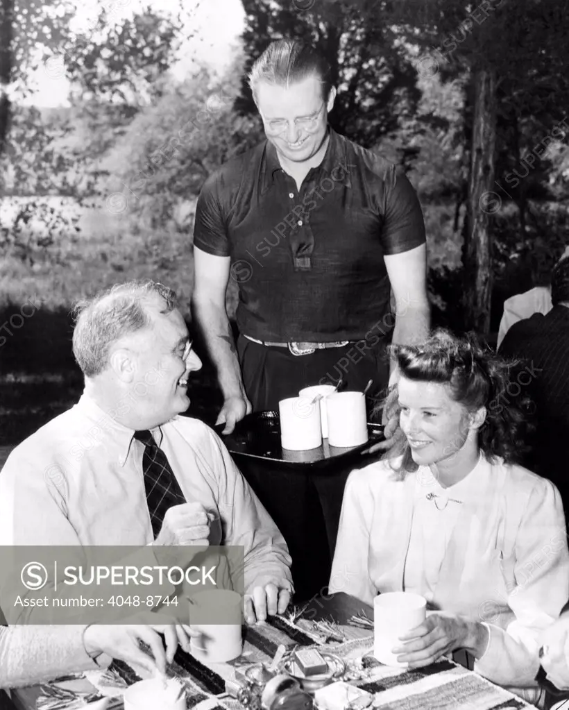 President Franklin Roosevelt lunching with Actress Katherine Hepburn at Val-Kil Cottage at the Hyde Park Estate. Elliott Roosevelt, FDR's son offers second helpings of fish chowder. A group of writers, actors and musicians were meeting at to arrange for a national radio show in support of the New Deal. Sept 22, 1940.