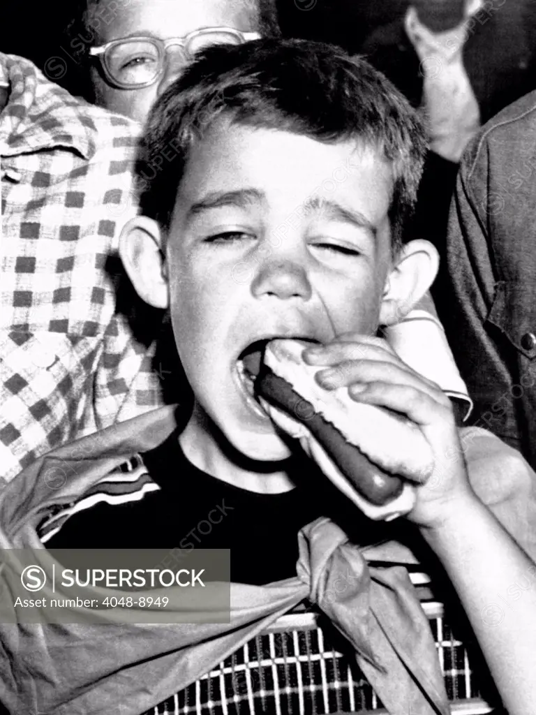 Dwight David Eisenhower II. He eats a hot-dog at a picnic given for him by his grandfather, President Eisenhower at Aksel Eielsen's Byers Peak ranch near Fraser, Colo. August 20, 1955.