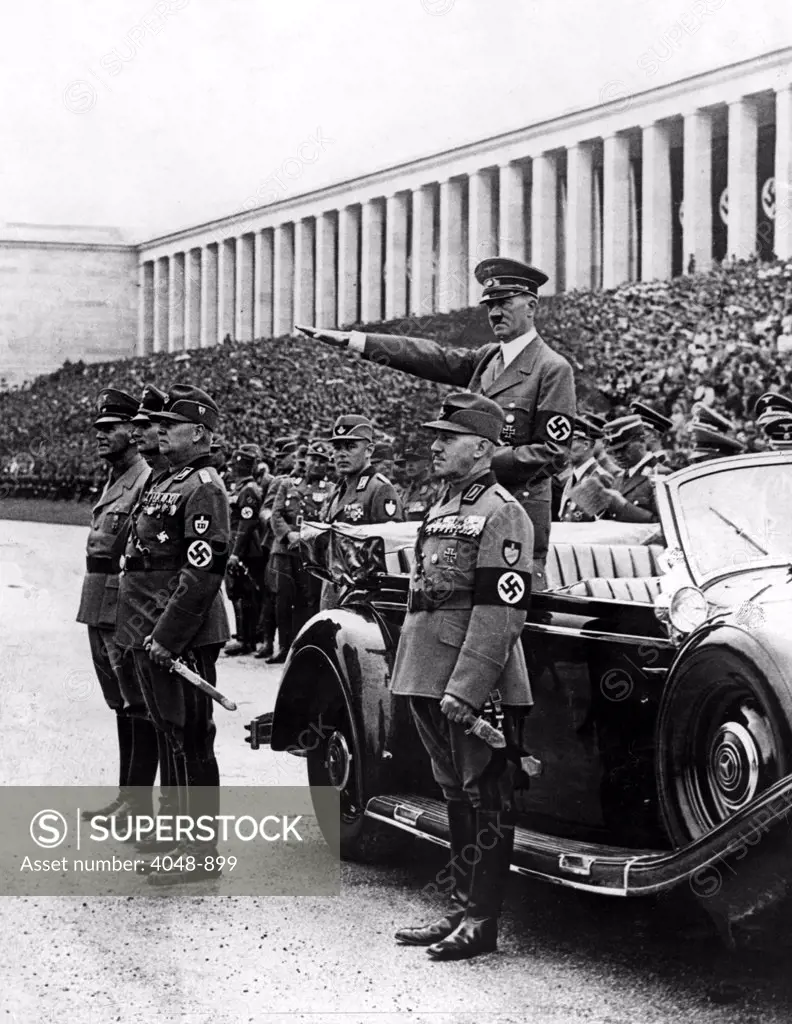 NUREMBERG, GERMANY--Chancellor Hitler (standing in car) salutes members of the Workers Corps as theymarched by during a review at Zeppelin Field, which was part of the ceremonies of the Annual Nazi Party Congress. 9/15/38.