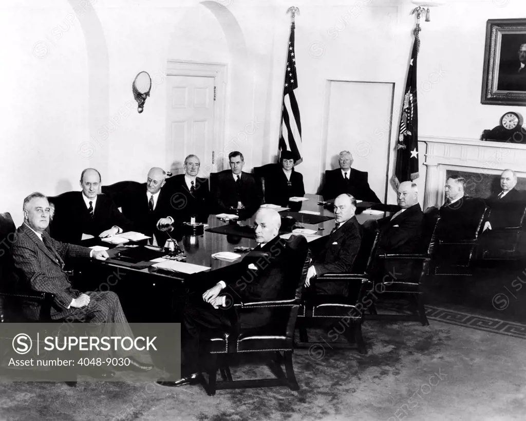 Franklin Roosevelt's second term Cabinet. At head of table is FDR. L-R on far side of table: Henry Morgenthau Jr.(Treasury), Homer Cummings (Attorney General), Claude Swanson (Navy), Henry Wallace (Agriculture), Francis Perkins (Labor). At foot of table is VP John N. Garner. L-R on near side of the table: Cordell Hull State), Harry Woodring (War), James Farley (Postmaster), Harold Ickes (Interior) and Daniel Roper (Commerce). March 8, 1937.