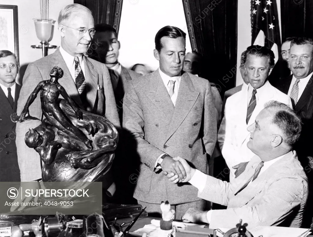 President Franklin Roosevelt shakes hands with Donald Douglas, the 1936 winner of the Collier Trophy. Douglass was awarded for the year's outstanding contribution aviation, the Douglas twin engine commercial transport plane. Standing L-R: Charles Hoorner, Pres. Of National Aeronautics Association, Donald Douglas, George Creel. July 1, 1936.