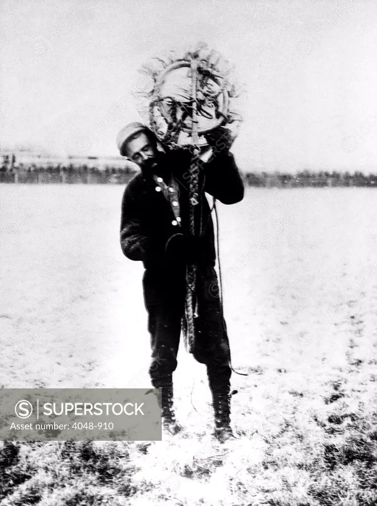 Albert Berry carries his parachute on his shoulder. He was the first person to jump from a plane with a parachute, 1912