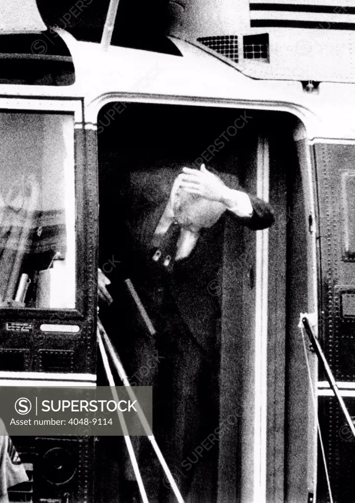 President Ford bumps his head after waving to reporters from his helicopter door on the White House lawn. October 22, 1974 .