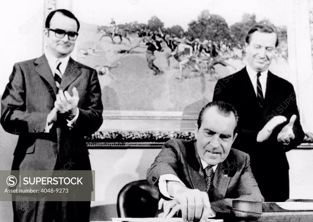 President Richard Nixon signs far reaching anti-pollution legislation. It will require the auto industry to produce virtually emission free cars by 1976. Applauding are William Ruckelshaus (left), head of the Environmental Protection Agency, and Russell Train, chairman of the Council on Environmental Quality. Dec. 31, 1970.