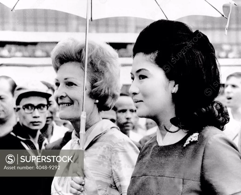 First Lady Pat Nixon (left) and Imelda Marcos stand under an umbrella at Manila airport. President Nixon conferred with Philippines President Marcos on the first stop of his seven nation world tour. July 27, 1969.