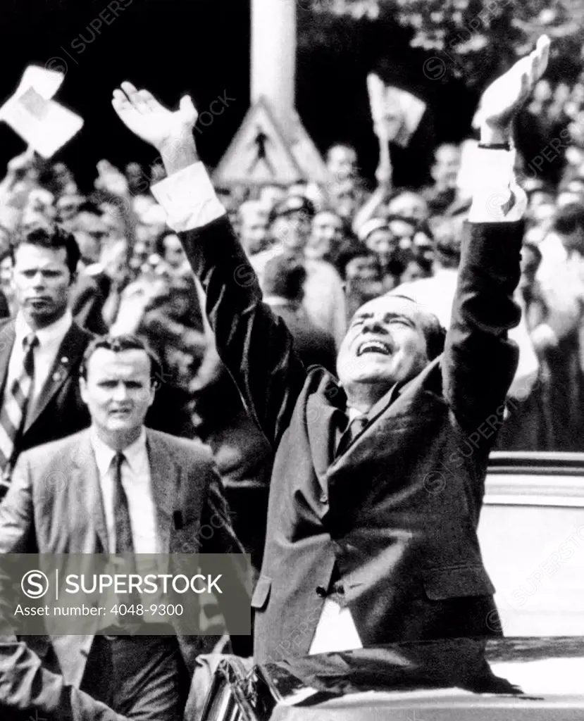 President Richard Nixon jubilantly acknowledges the cheers of apartment house dwellers as his motorcade proceeds through Bucharest. August 2, 1969.