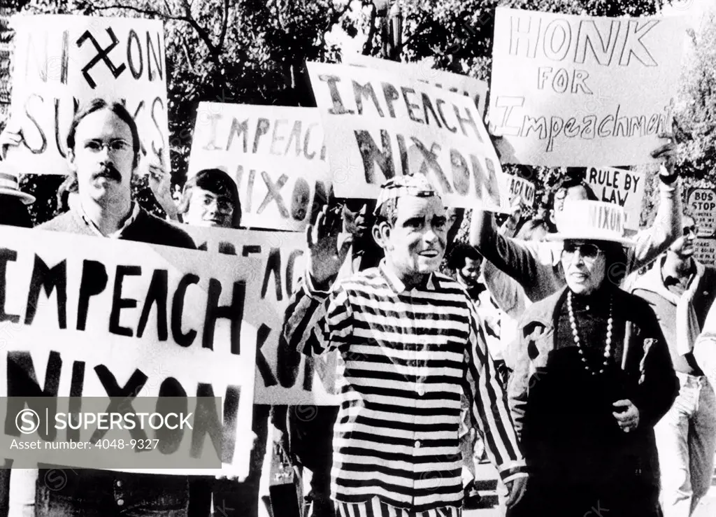 Anti-Nixon demonstrators at the White House. One demonstrator wears a Nixon mask and a striped prison uniform. They protested Nixon's dismissal of independent special prosecutor Archibald Cox, and the resignations of Attorney General Elliot Richardson and Deputy Attorney General William Ruckelshaus. Oct. 22, 1973.