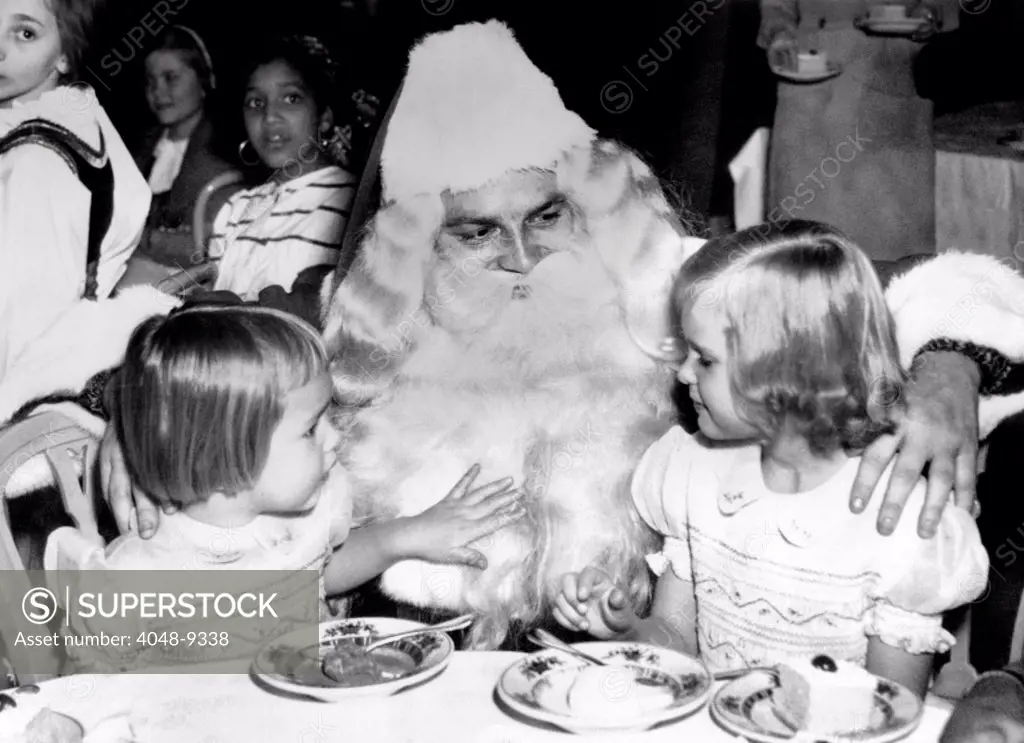 Julie, 4, and Patricia, 6, daughters of Vice President-elect Richard Nixon, with Santa Claus. The girls were at the annual International Children's Christmas broadcast. Dec. 21, 1952.