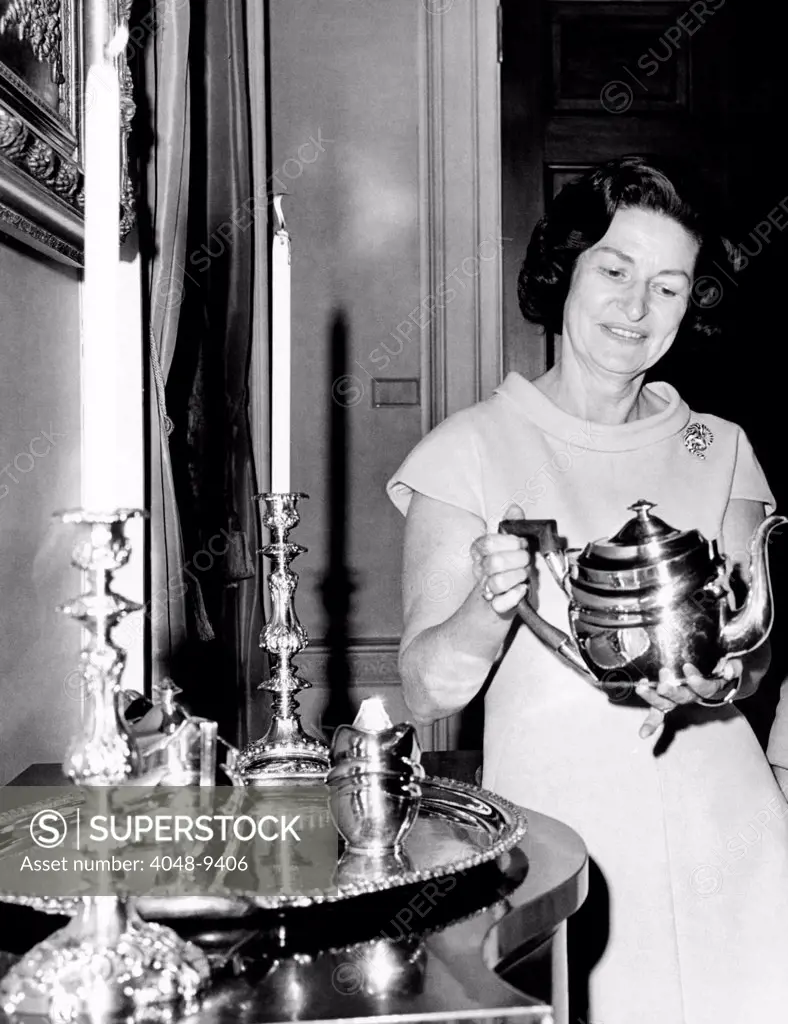 Lady Bird Johnson holds a silver teapot made by Issac Hutton. Made in New York City, the three piece set was donated to the White House by Mrs. Oscar Cox. Nov. 13, 1967