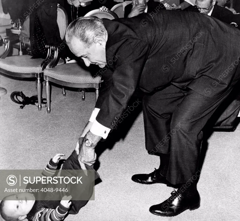 President Lyndon Johnson tugs the legs of his baby grandson, Lyndon Patrick Nugent. In the background is the audience remaining from the ceremony marking the 25th anniversary of the release of atomic energy, at the University of Chicago in 1942. Dec. 2, 1967.