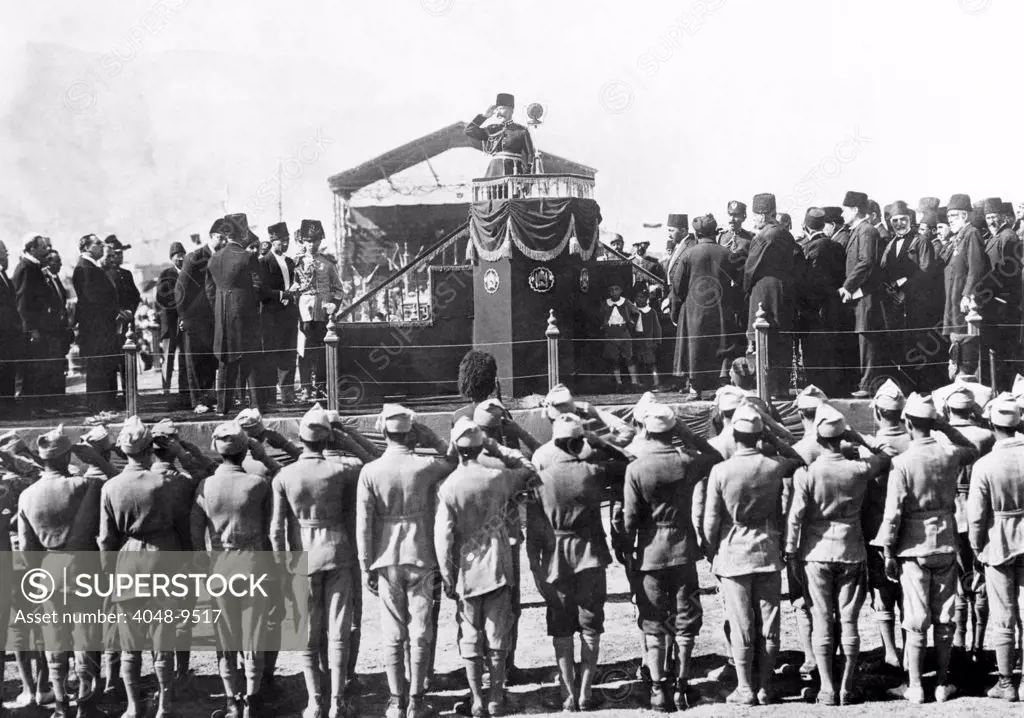 Afghanistan Independence Day celebration in Kabul. His Majesty Nadir Khan returning the salute during the troop review. On the platform with the King are members of his court, army officers, and foreign diplomats. Nov. 6, 1931.