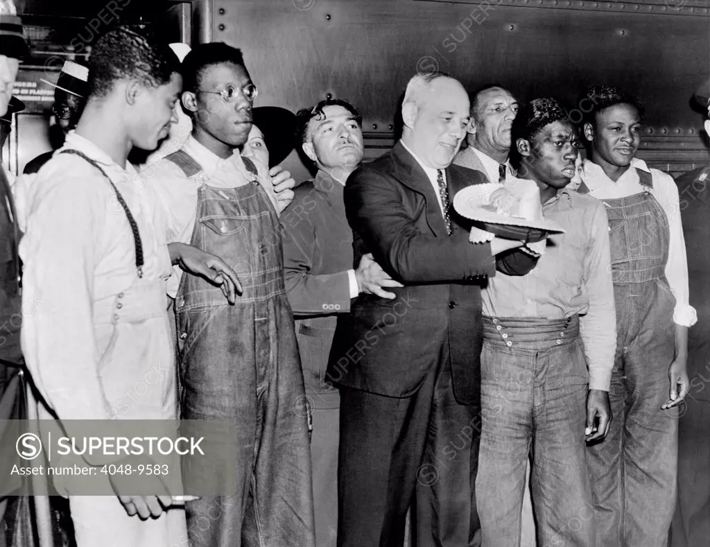 Scottsboro Boys' and radical lawyer Samuel Leibowitz cheer at Penn Station. After a six year battle in Alabama and Federal Courts, four of the nine youths were freed this week of charges of assault. L-R: Eugene Williams, Olen Montgomery, Attorney Leibowitz, who is destroying his straw hat in jubilation, Willie Roberson, and Roy Wright. July 26, 1937.