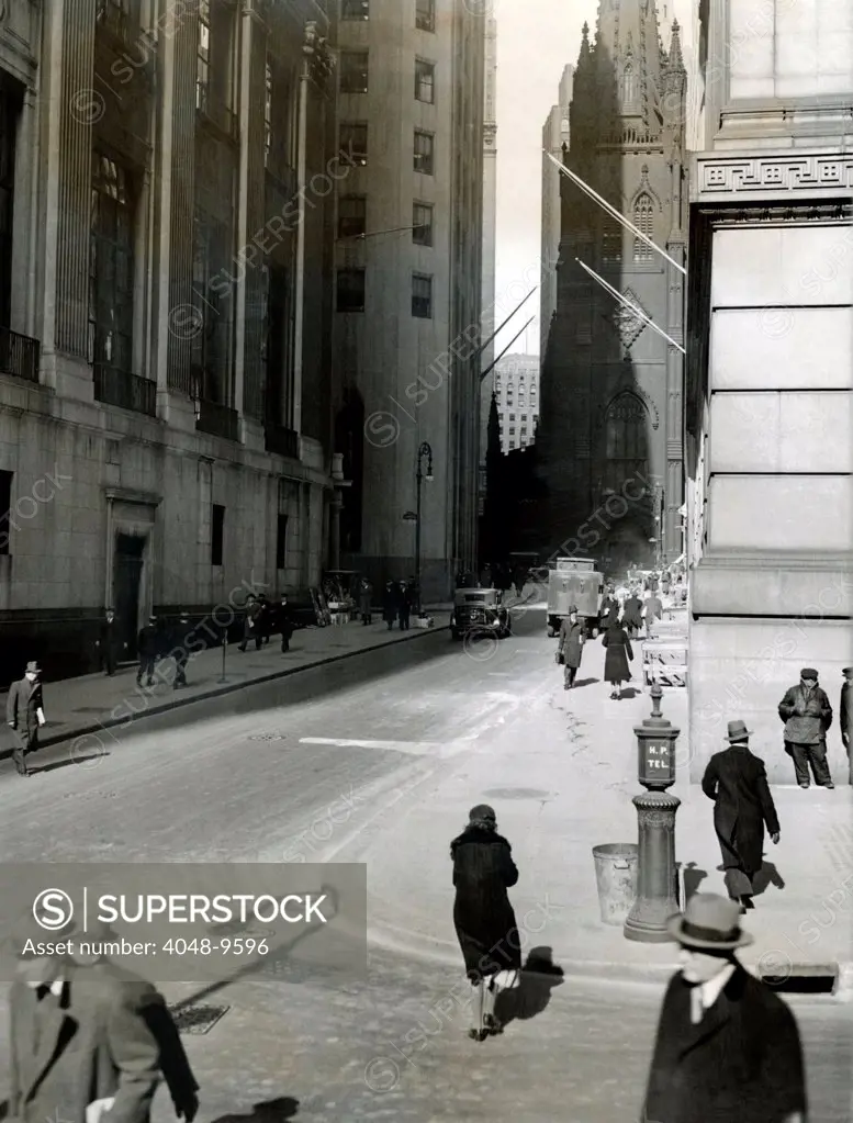 Wall Street on March 10, 1933 during the New Deal 'Bank Holiday'. Usually crowded, the streets are relatively empty, following the closing of banks and the stock brokerage houses. Trinity Church is in the background.