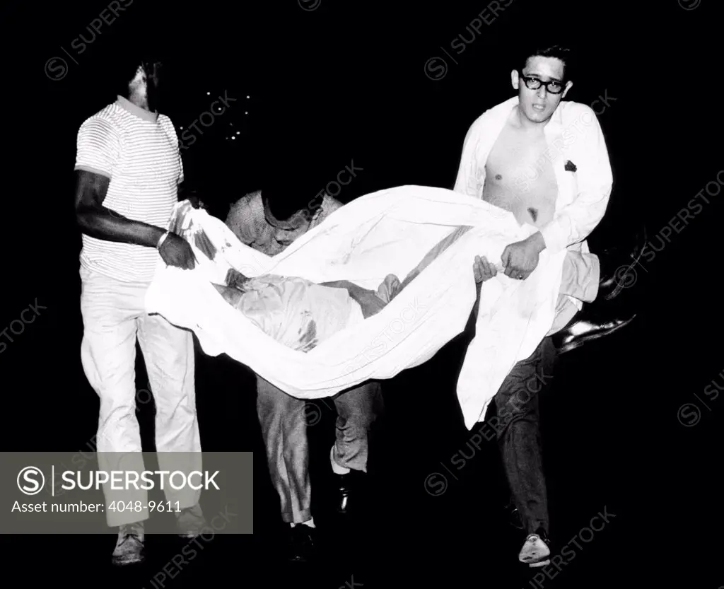 Three men carry body of a youth who died after apparently falling from a rooftop during third night of civil disorder in Spanish Harlem on July 25, 1967.