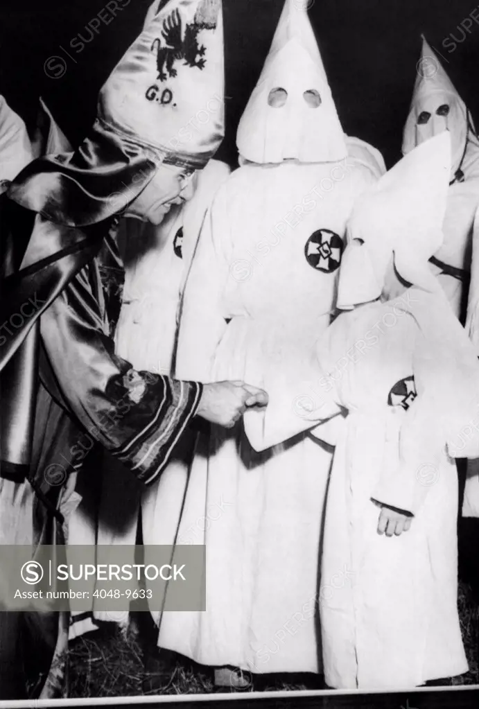 Dr. Samuel Green (left), Grand Dragon of the Ku Klux Klan, greets a small boy dressed in Klansmans robes. The boy was one of many children so dressed to attend the mass initiation. Stone Mountain, Georgia. June 14, 1949.
