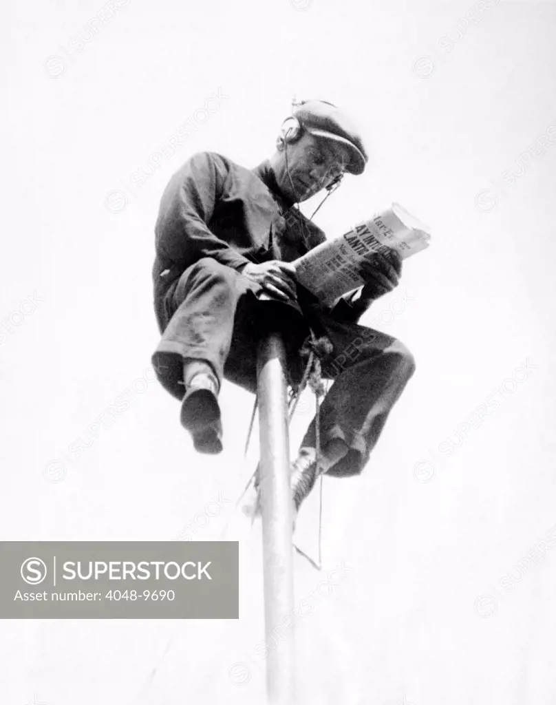 Alvin 'Shipwreck' Kelly sitting on a 39 foot flagpole atop the eight-story Hotel St. Francis in Newark. He planned to beat his 7 day record by sitting for eight days, and exceeded the goal by lasting for 12 days. He sat on a 20 inch wide perch with coffee, water, and cigarettes. Kelly is on the Loew Vaudeville circuit. July 5, 1927.