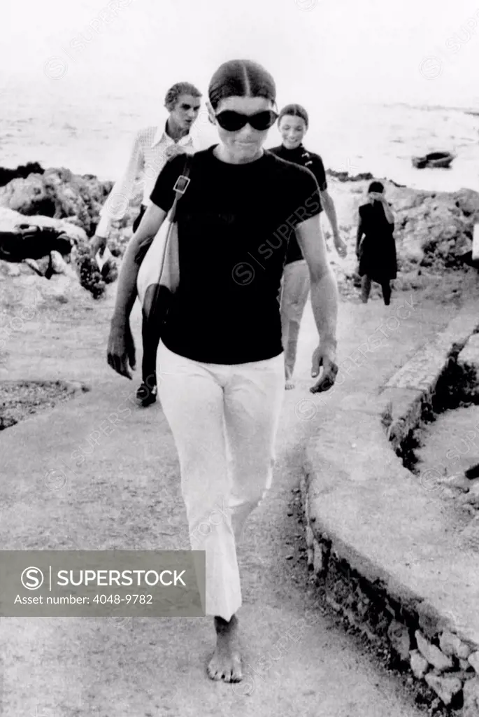 Jacqueline Kennedy Onassis on vacation in Capri, Italy. A barefooted Mrs. Jacqueline Onassis walks along the dock of this island resort. Behind her is her sister Lee Radziwill. August 24, 1970.