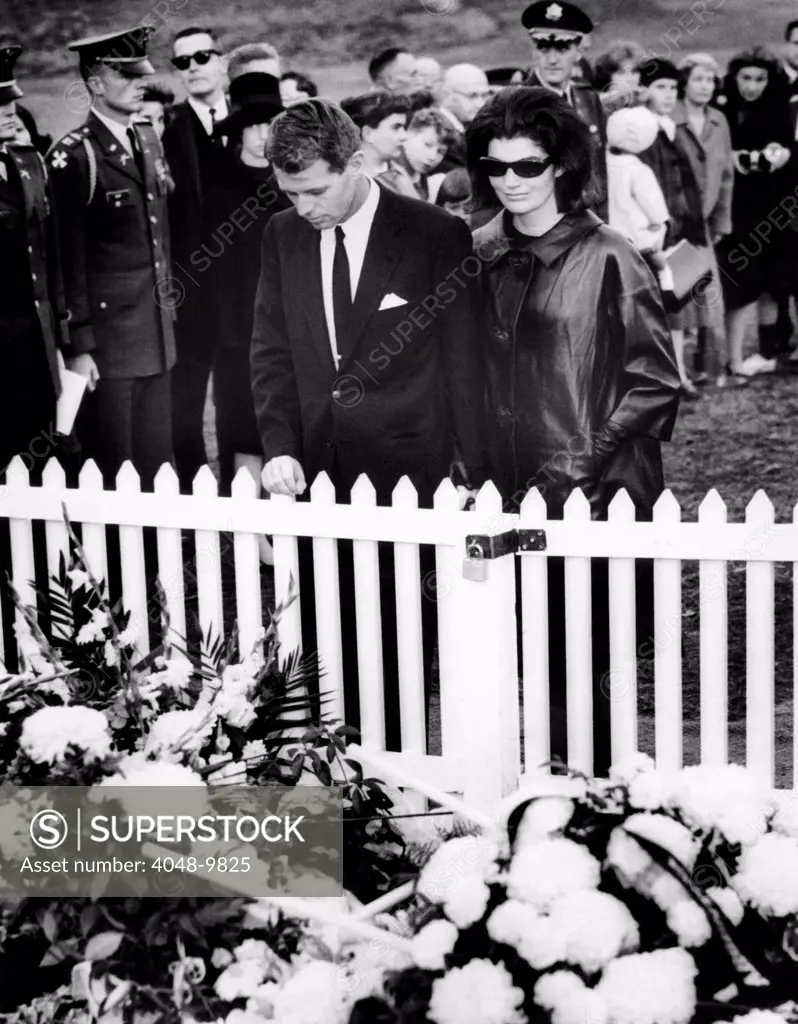 Jacqueline Kennedy and Attorney General Robert Kennedy visit the flower covered grave of President John Kennedy at Arlington National Cemetery. Nov. 27, 1963.