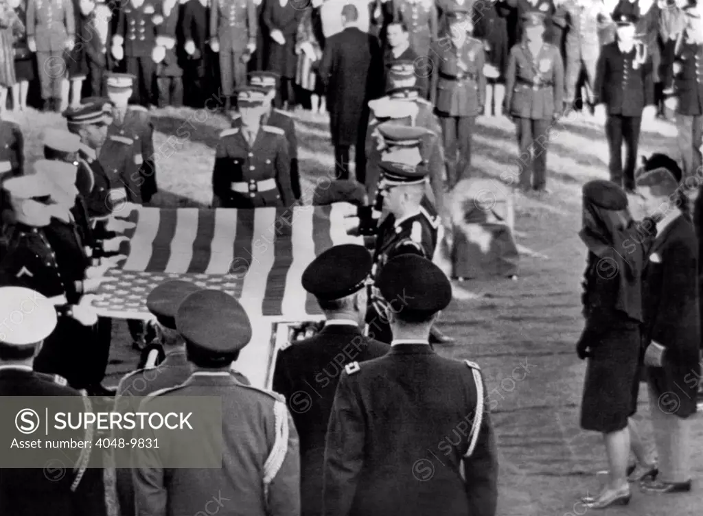 Jacqueline Kennedy stands forward as the flag from her husband's coffin is raised for folding. She accepted the flag at the end of President John Kennedy's burial ceremony in Arlington National Cemetery. Nov. 25, 1963.