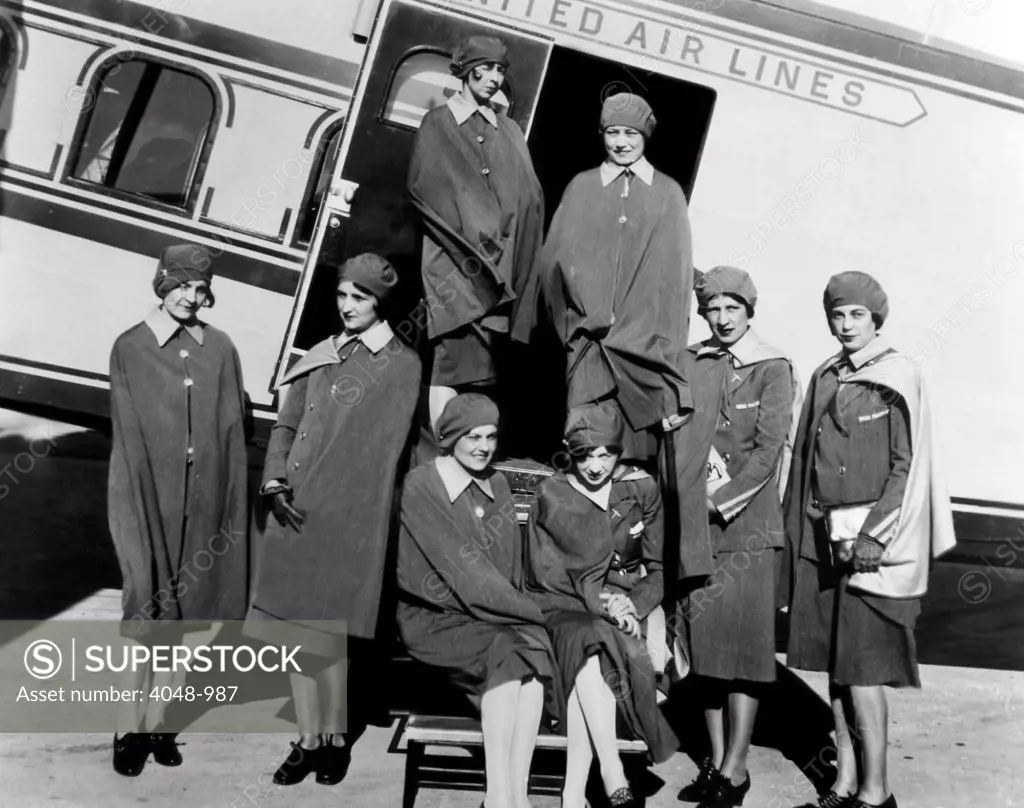 Some of the first stewardesses for United Airlines, known as 'skygirls', standing next to a Boeing tri-motored plane, 1930