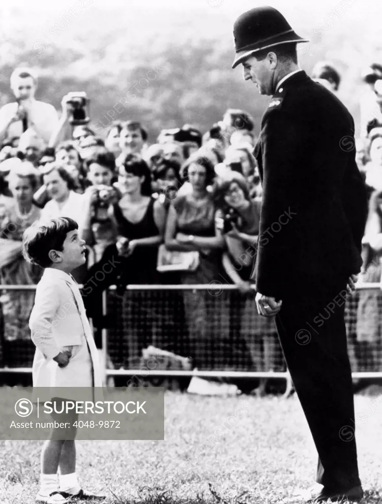 John F. Kennedy Jr. looks up at a British policeman during dedication ceremonies of a memorial to the late President Kennedy, at Runnymede, England. May 14, 1965.