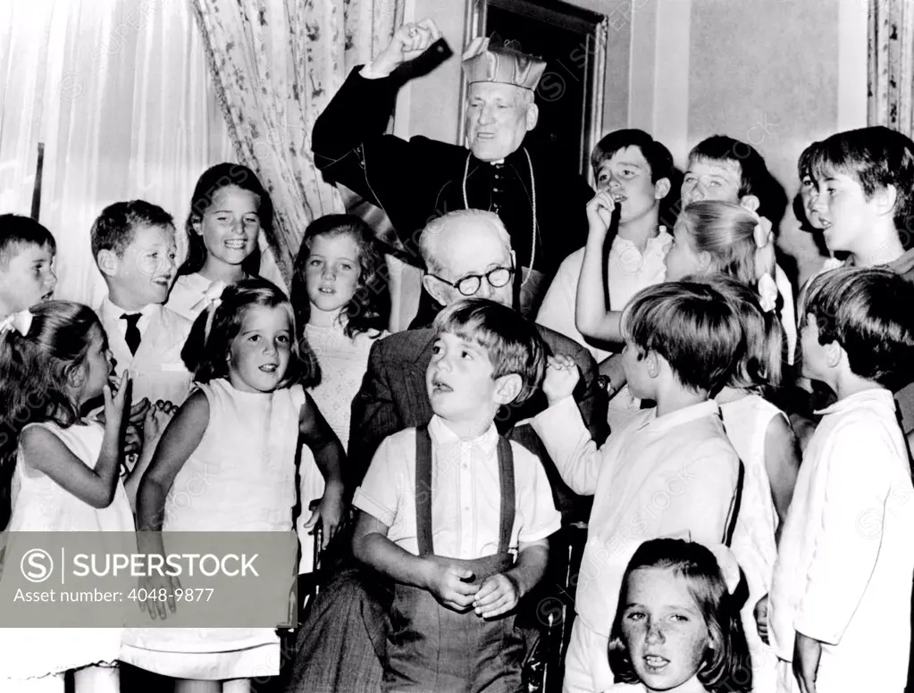 Cardinal Richard Cushing leads the Kennedy children in singing 'Happy Birthday'. They were celebrating their grandfather's 70th birthday. Former Ambassador Joseph P. Kennedy is partially hidden by John F. Kennedy Jr. Aug. 24, 1965.