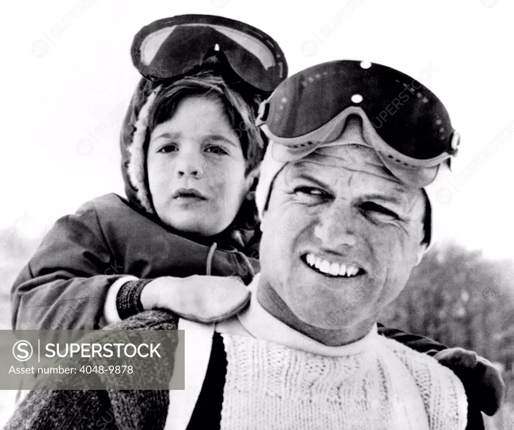 Ted Kennedy gives his nephew John F. Kennedy Jr. a piggy-back ride down the ski slopes in Stowe, Vermont. The Kennedy family spent Easter weekend skiing together. March 29, 1964.