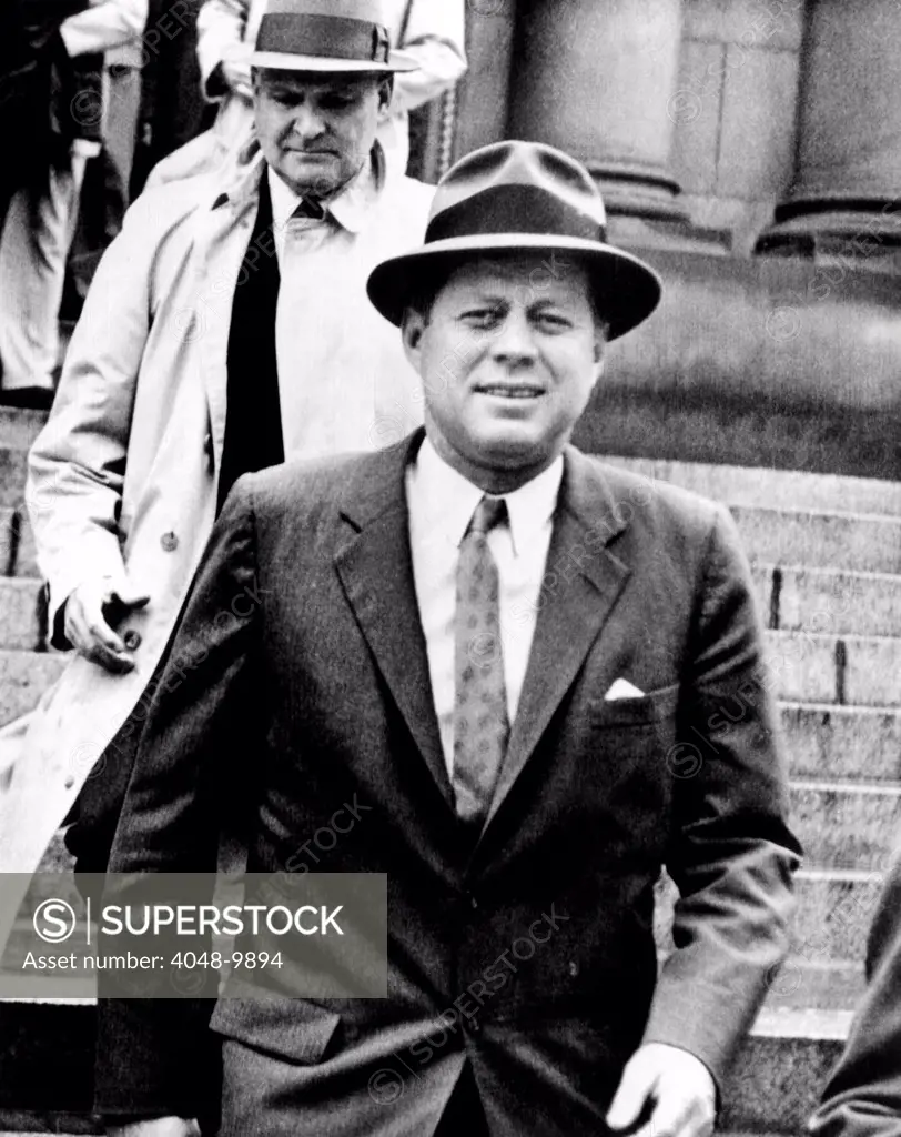President Kennedy wearing a Fedora. He was leaving St. Mathews Cathedral in rainy weather. May 11, 1961