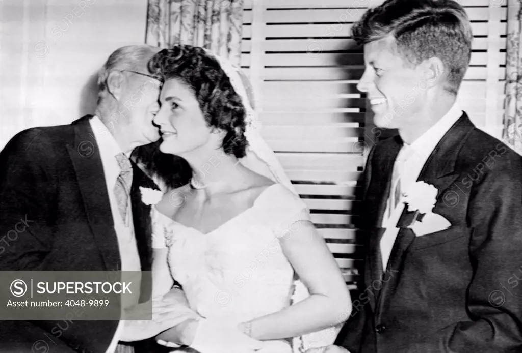 Joseph P. Kennedy kisses his new daughter-in-law, the former Jacqueline Lee Bouvier. The groom, his son, Senator John Kennedy is at right. Sept. 12, 1953.