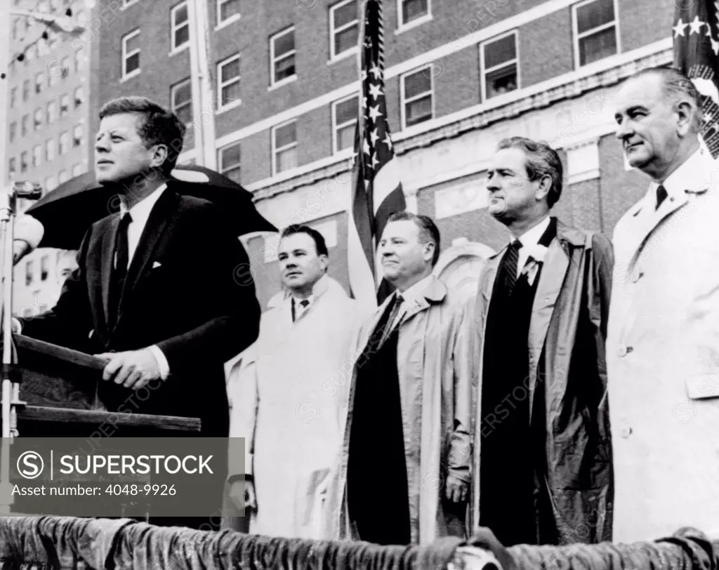 Morning of the day of JKF's assassination. President Kenney speaks to a crowd in front of the Texas Hotel in Fort Worth during a light rain. Behind him are (L-R): Senator Ralph Yarborough; Texas Governor John Connally, and Vice President Lyndon Johnson. Nov. 22, 1963